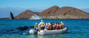 Sullivan bay in Santiago Island, view of many travelers in a Panga and in the background the Coral Yacht